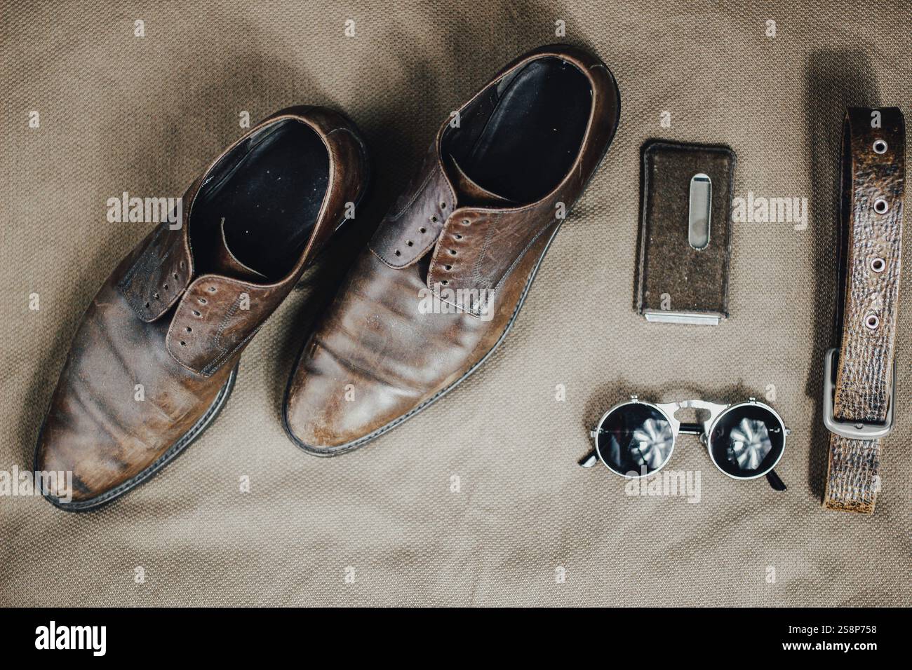 Vintage leather shoes with stylish accessories on an earthy textured surface Stock Photo