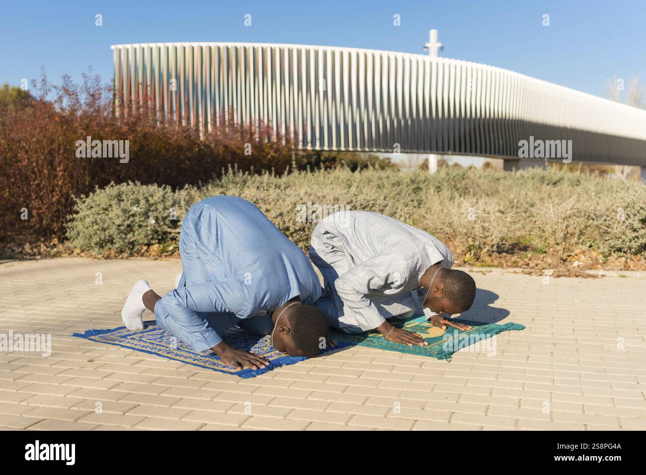 Two young senegalese men wearing traditional clothing are kneeling on ...