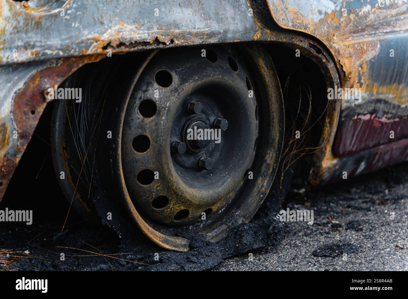 Burnt and destroyed car. Close-up of burnt wheel. Black charred tire ...