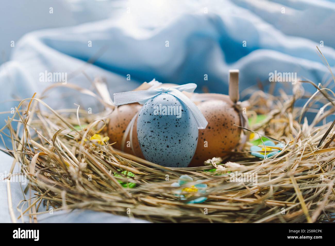 Colorful Easter eggs nestled in a nest surrounded by flowers and straw ...