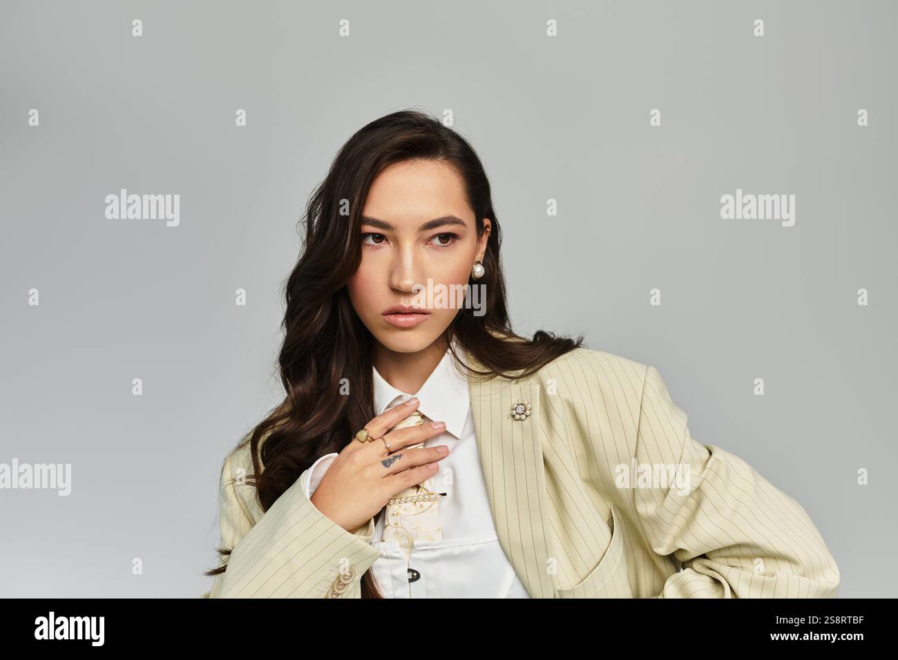 A stylish young woman poses gracefully in a tailored outfit, radiating ...