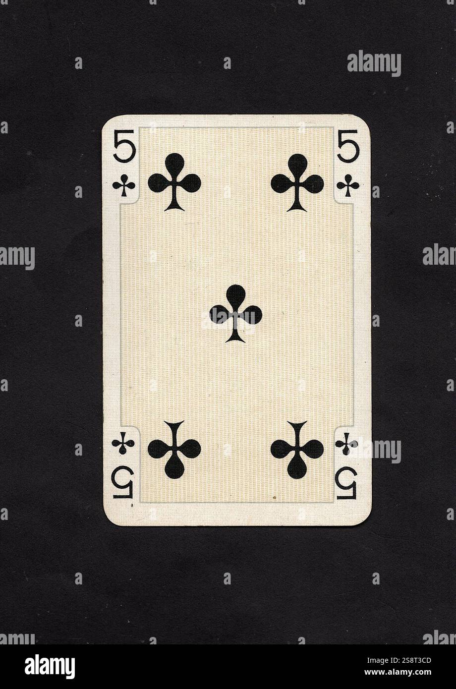 An antique five of clubs playing card isolated on a black background ...