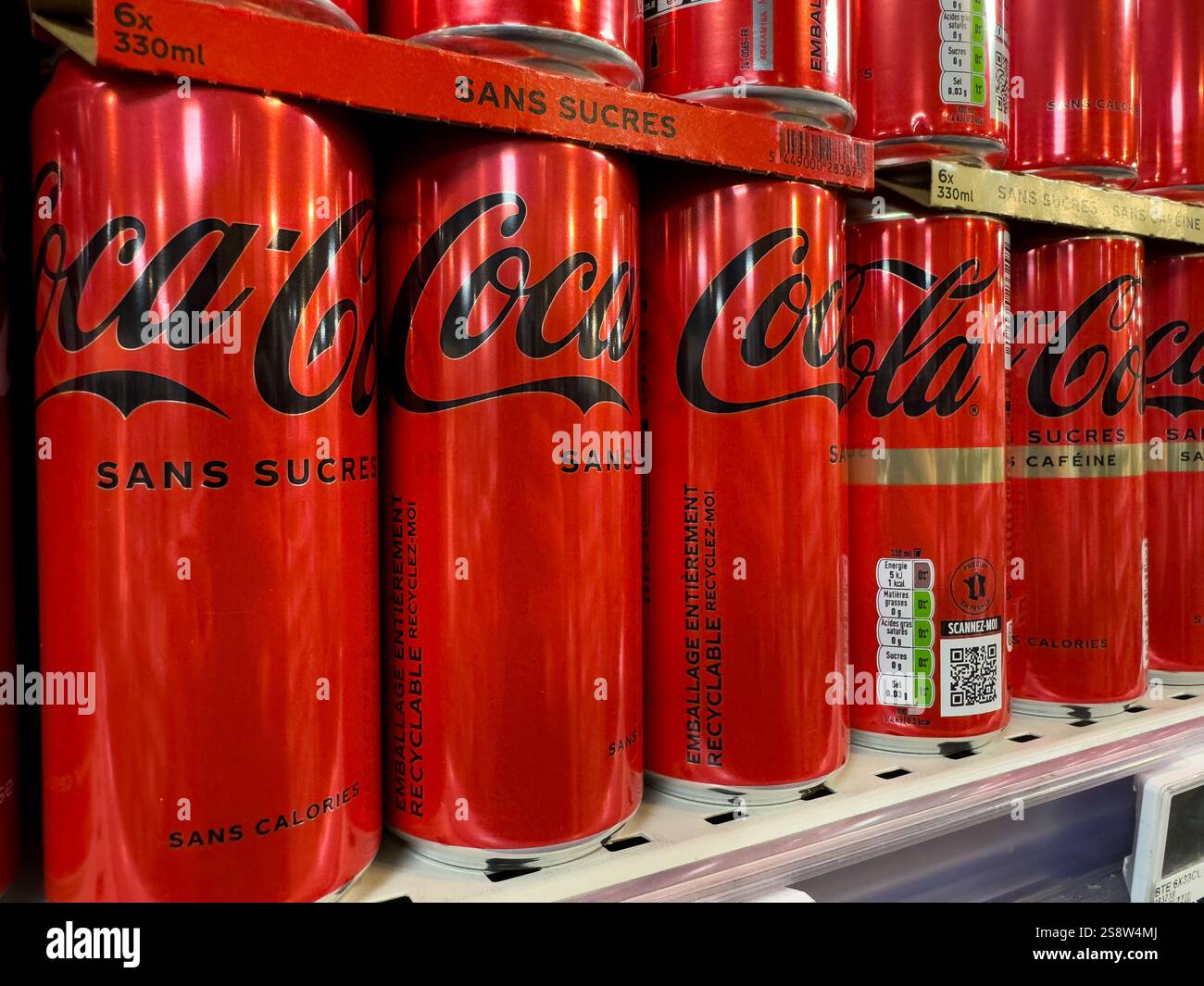 Red cans lined up on shelf in a grocery store displaying soda products ...
