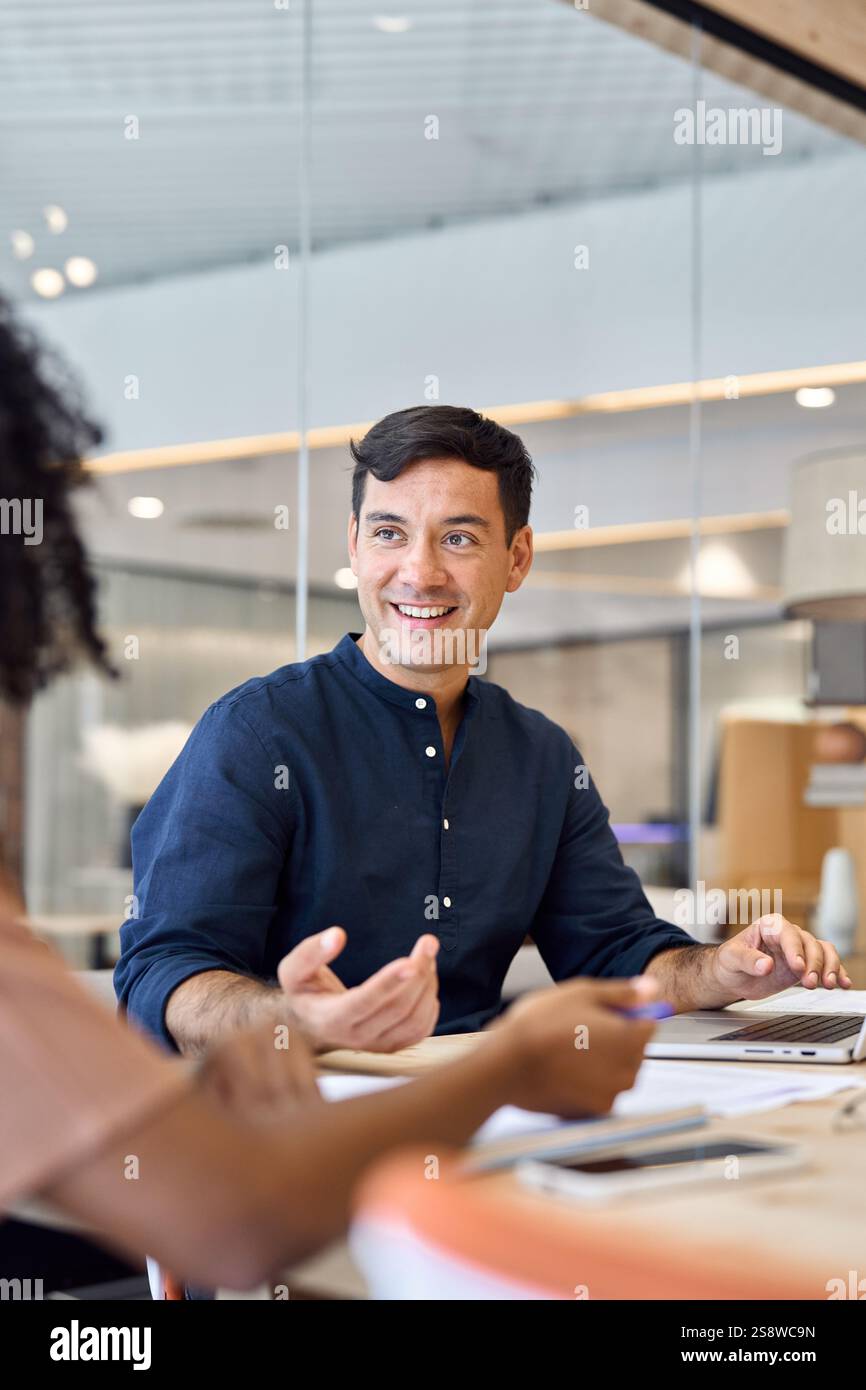 Young happy Hispanic business man manager working with colleague at meeting. Stock Photo