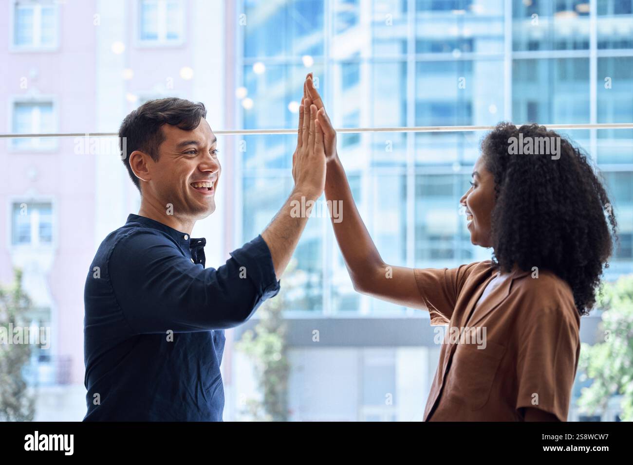 Two happy diverse team business people giving high five standing in ...