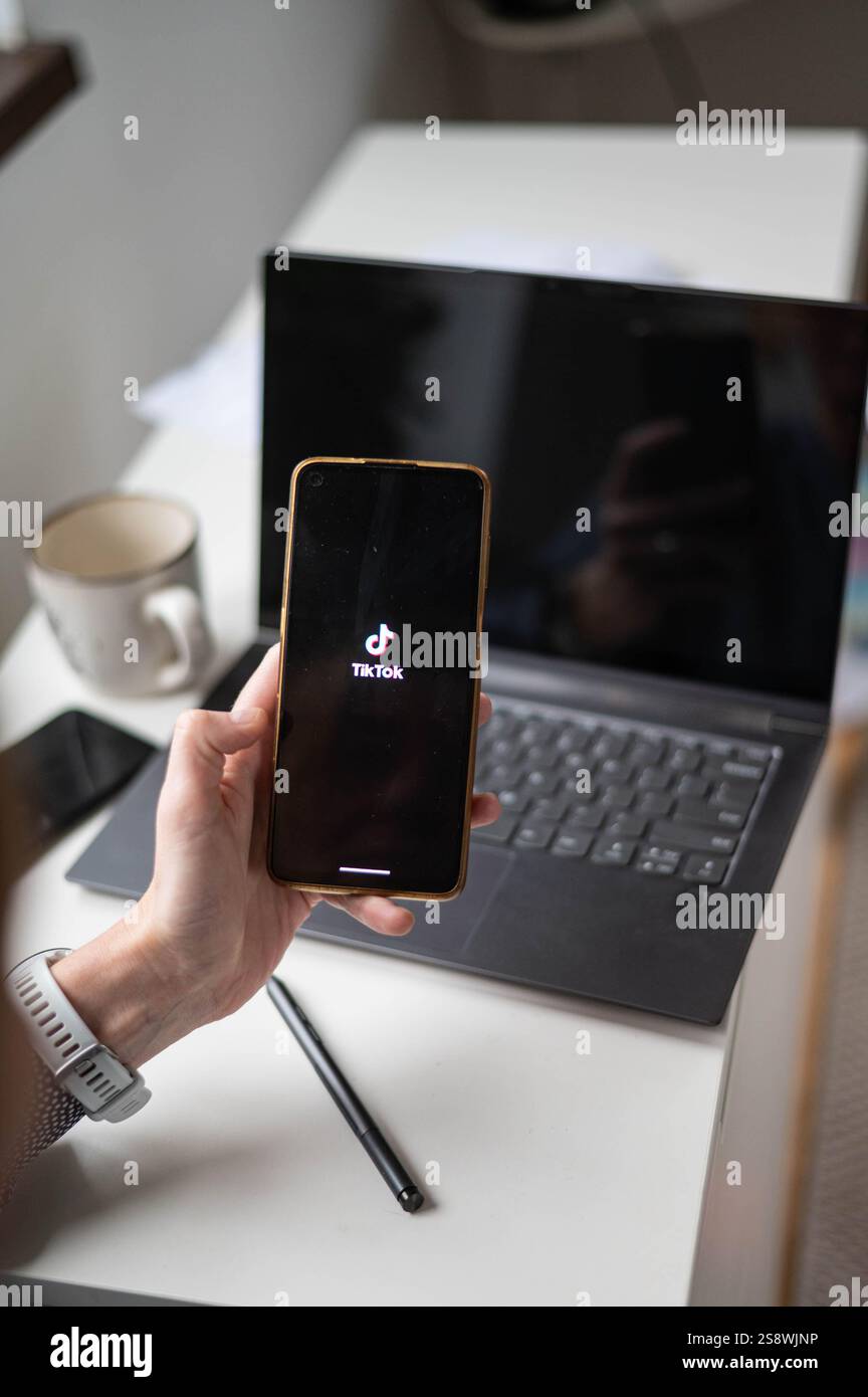 woman using phone showing  application on screen and laptop Stock Photo