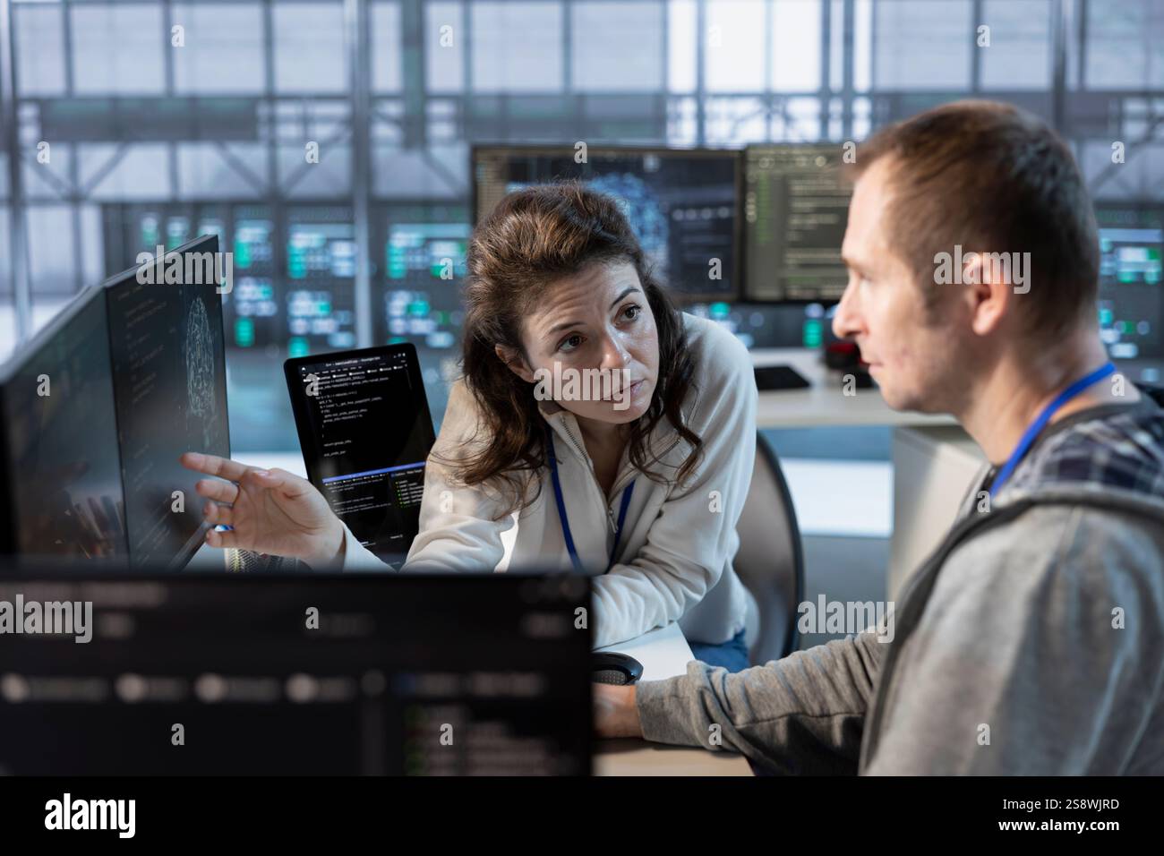 Teamworking colleagues using machine learning to optimize data center operations, improving efficiency of infrastructure. Manager discussing with worker, implementing server virtualization Stock Photo
