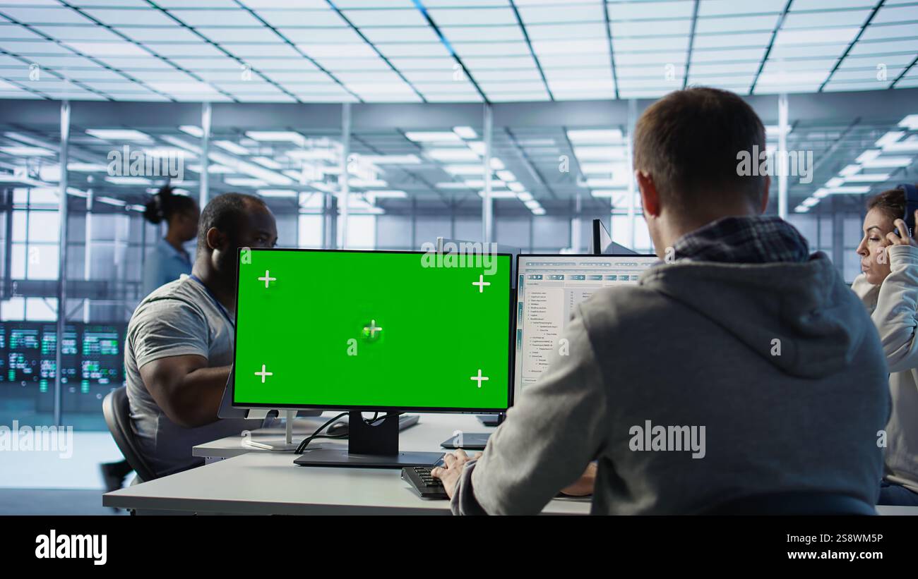 Engineer in server hub using green screen PC to repair equipment storing datasets. Professional using mockup computer to do debugging on rigs doing computational operations, camera B Stock Photo