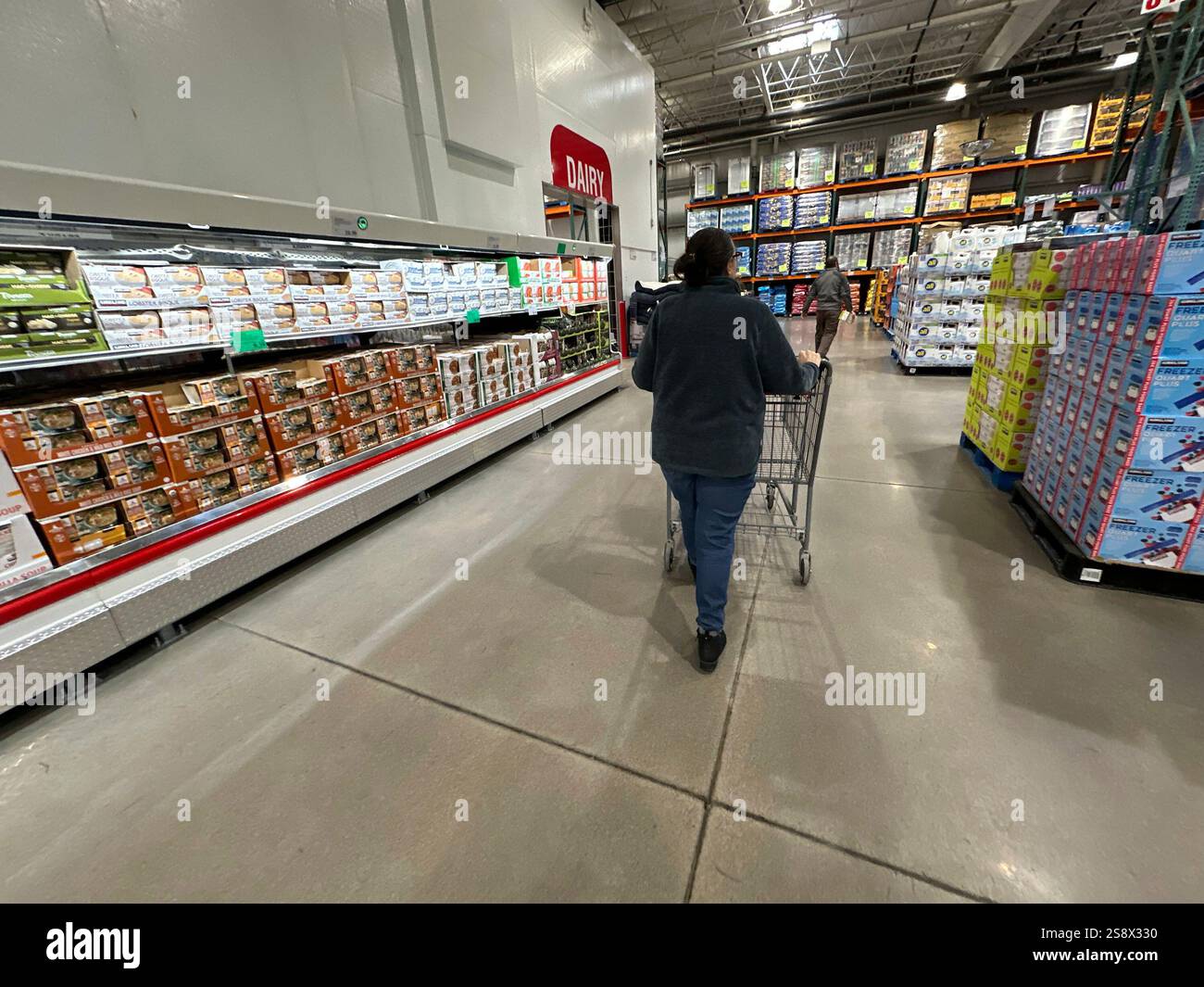 A shopper pushes a cart past a display of soups in a Costco warehouse ...