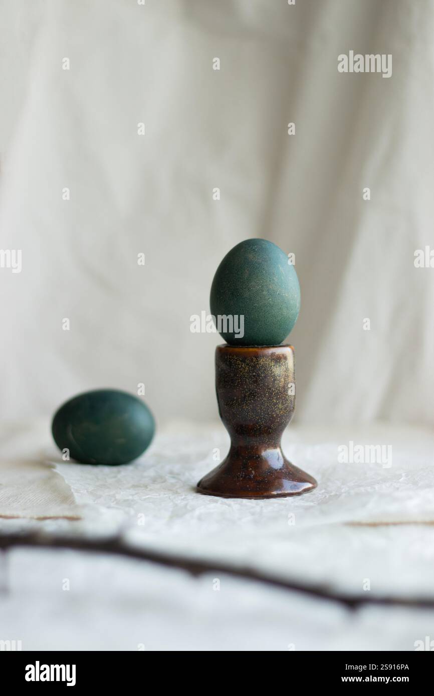 Green naturally dyed Easter egg in a rustic ceramic holder. Stock Photo