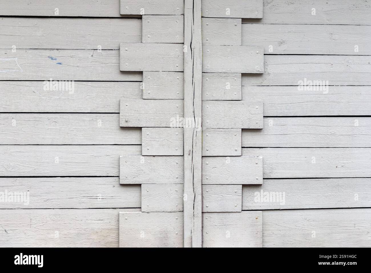 A fragment of a wooden plank wall painted in white with an interesting geometric pattern. Stock Photo