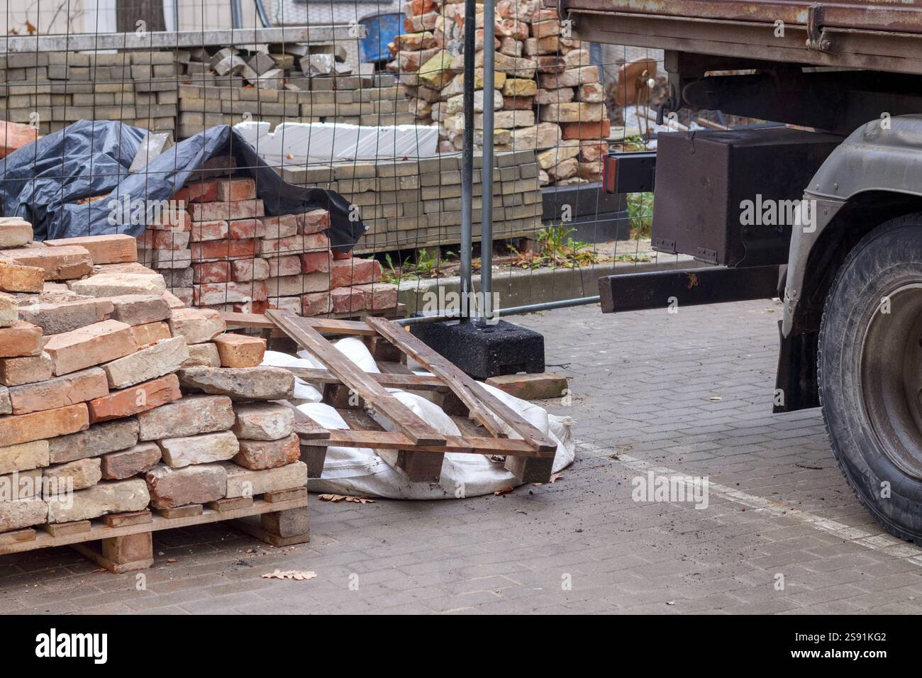A construction site with bricks and a truck stacked on pallets. Stock Photo