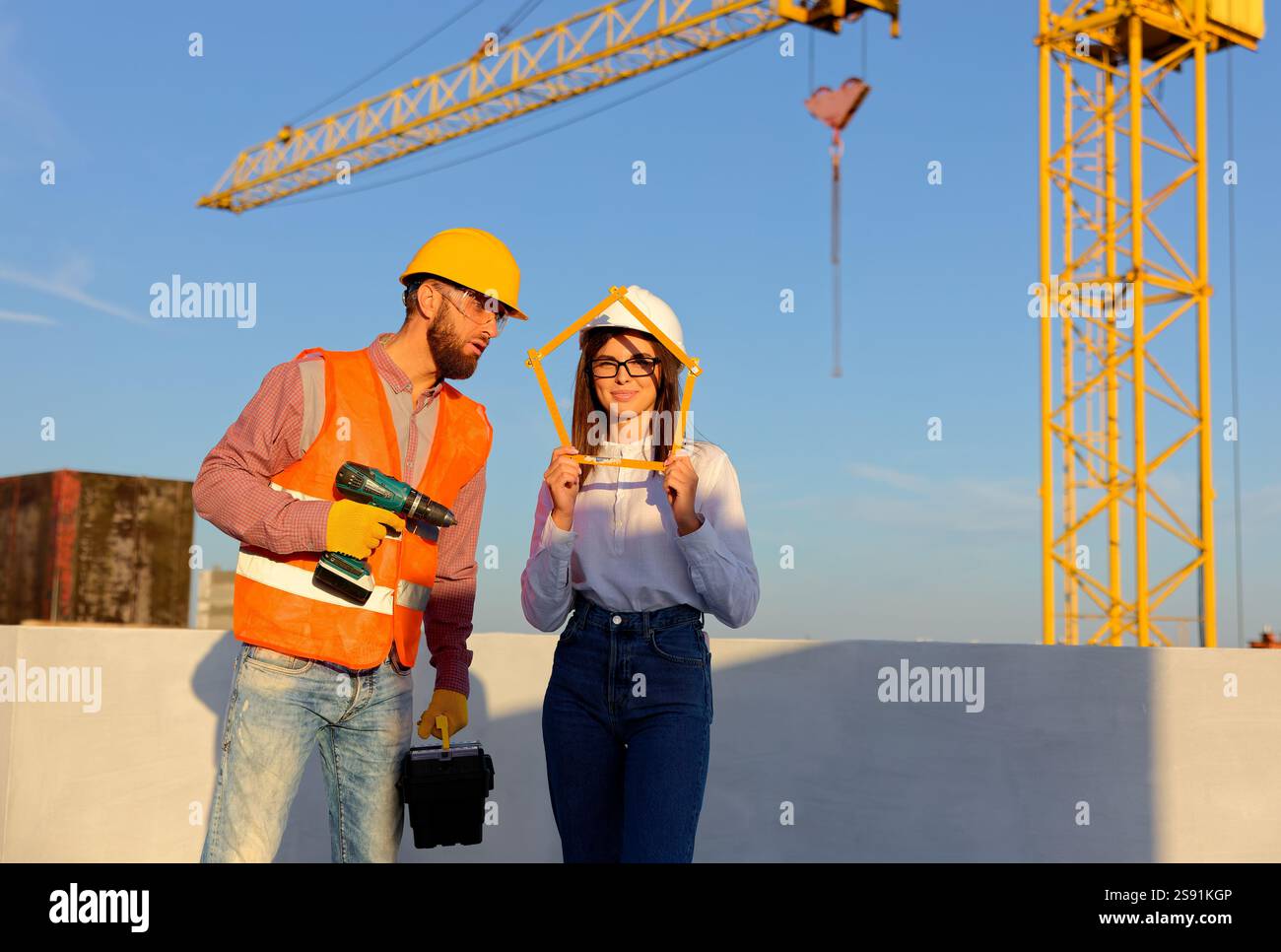 Construction workers are posing at building site holding folding ruler ...