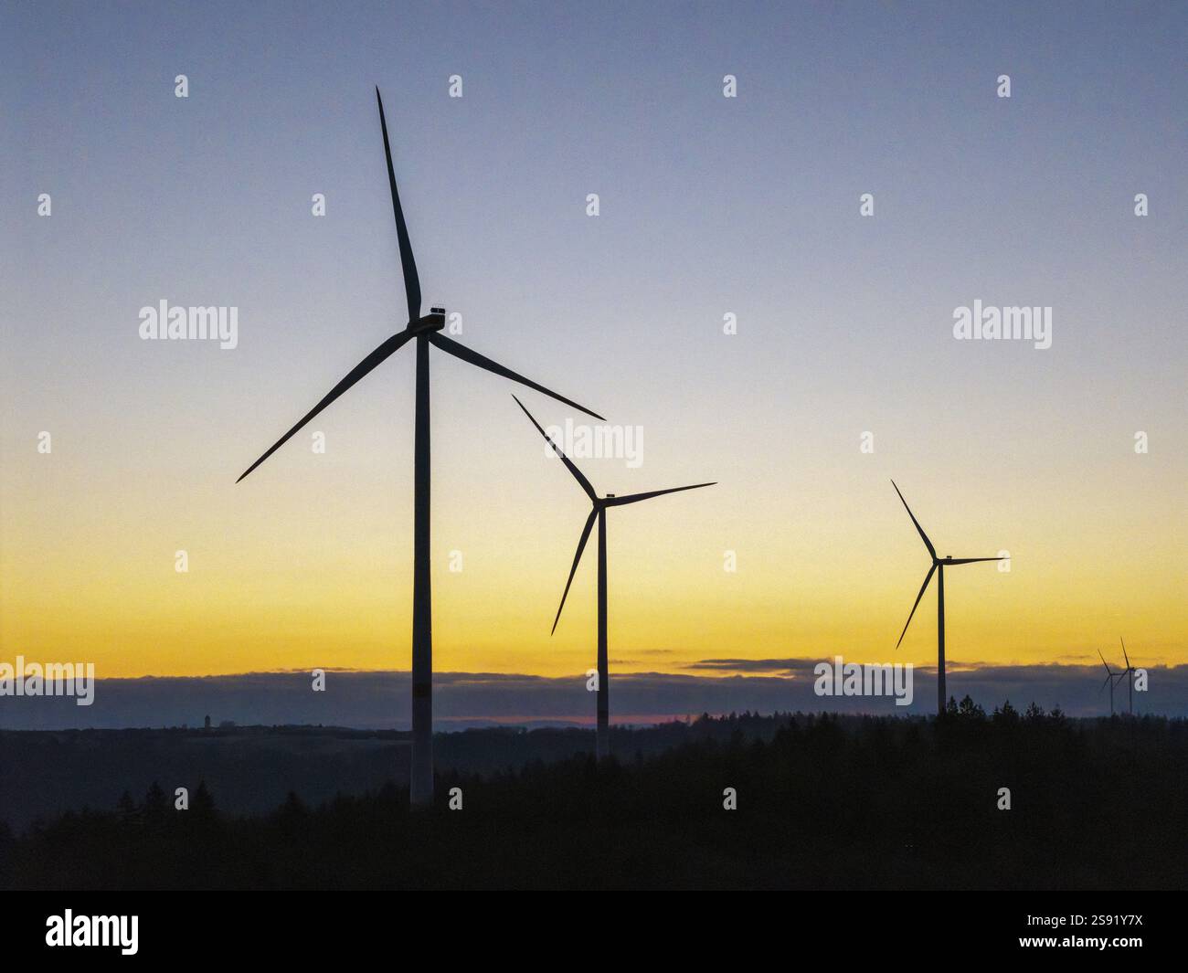 Silhouettes of wind turbines in front of a golden sunrise sky, Rems ...
