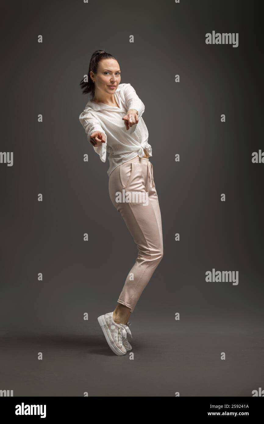 Young and beautiful dancer posing in studio at grey background Stock Photo