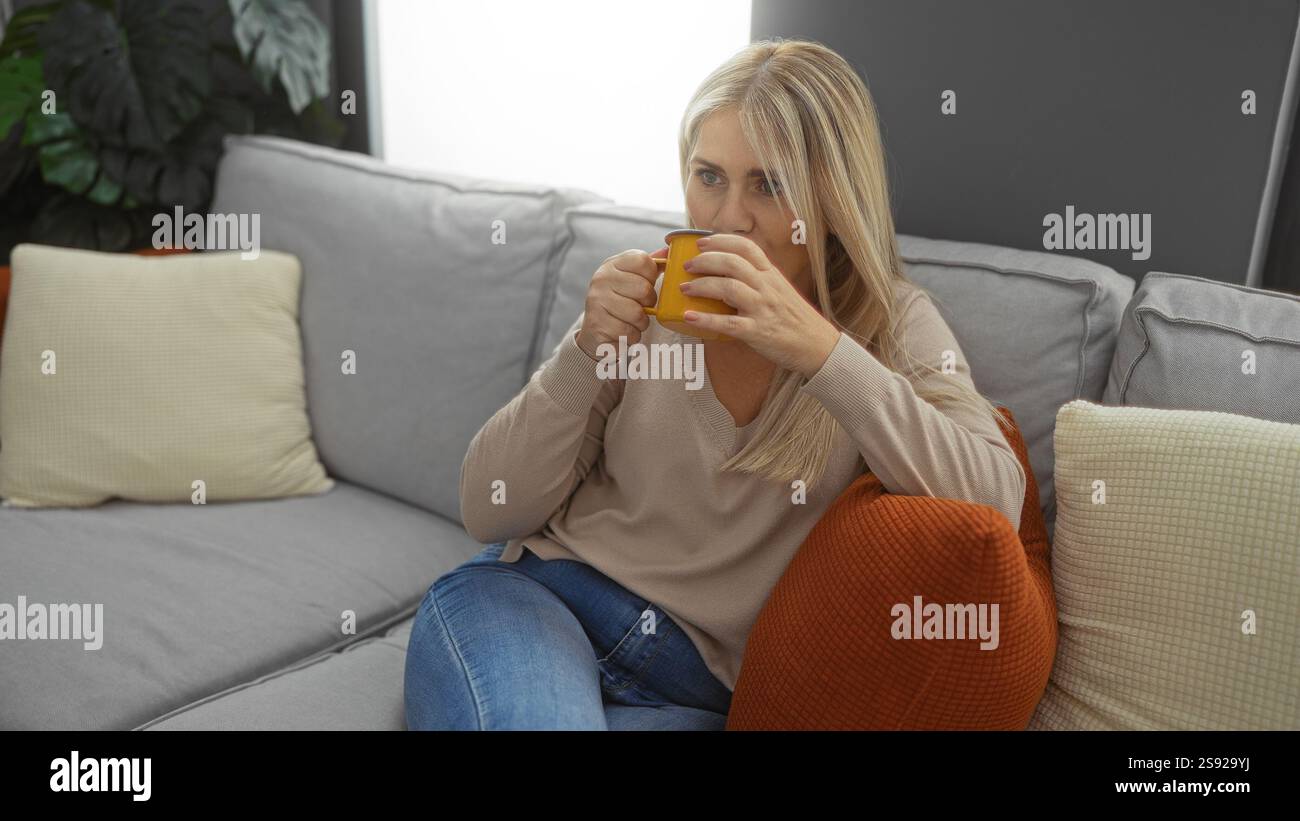 Woman relaxing in living room sipping drink on cozy sofa with blonde ...