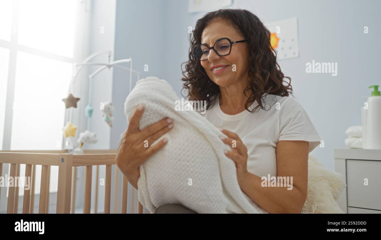 Woman smiling while holding baby in cozy bedroom with cradle nearby ...