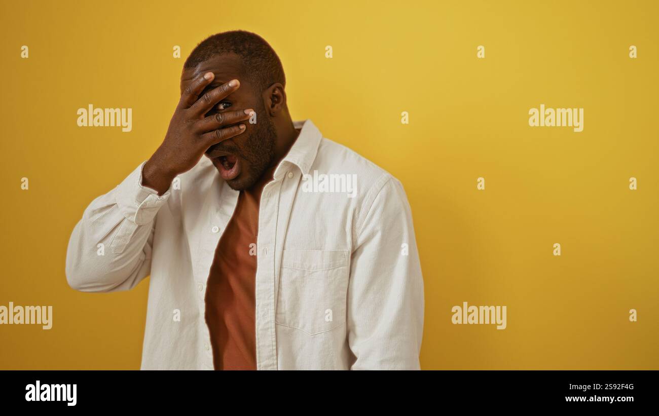 Young man surprised, covering his eyes with one hand against a vibrant ...