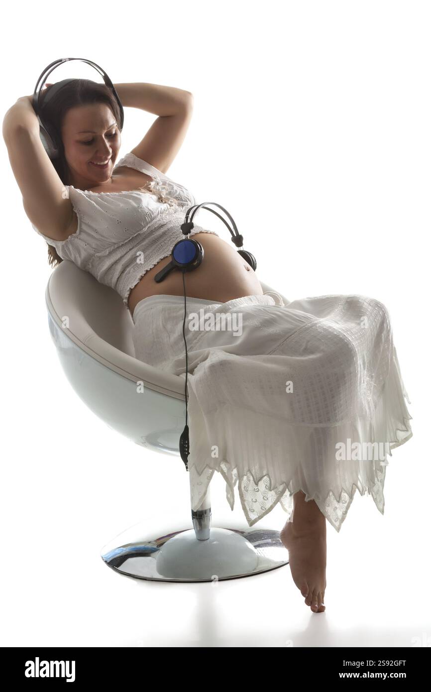 Pregnant woman listening to music on white background Stock Photo - Alamy