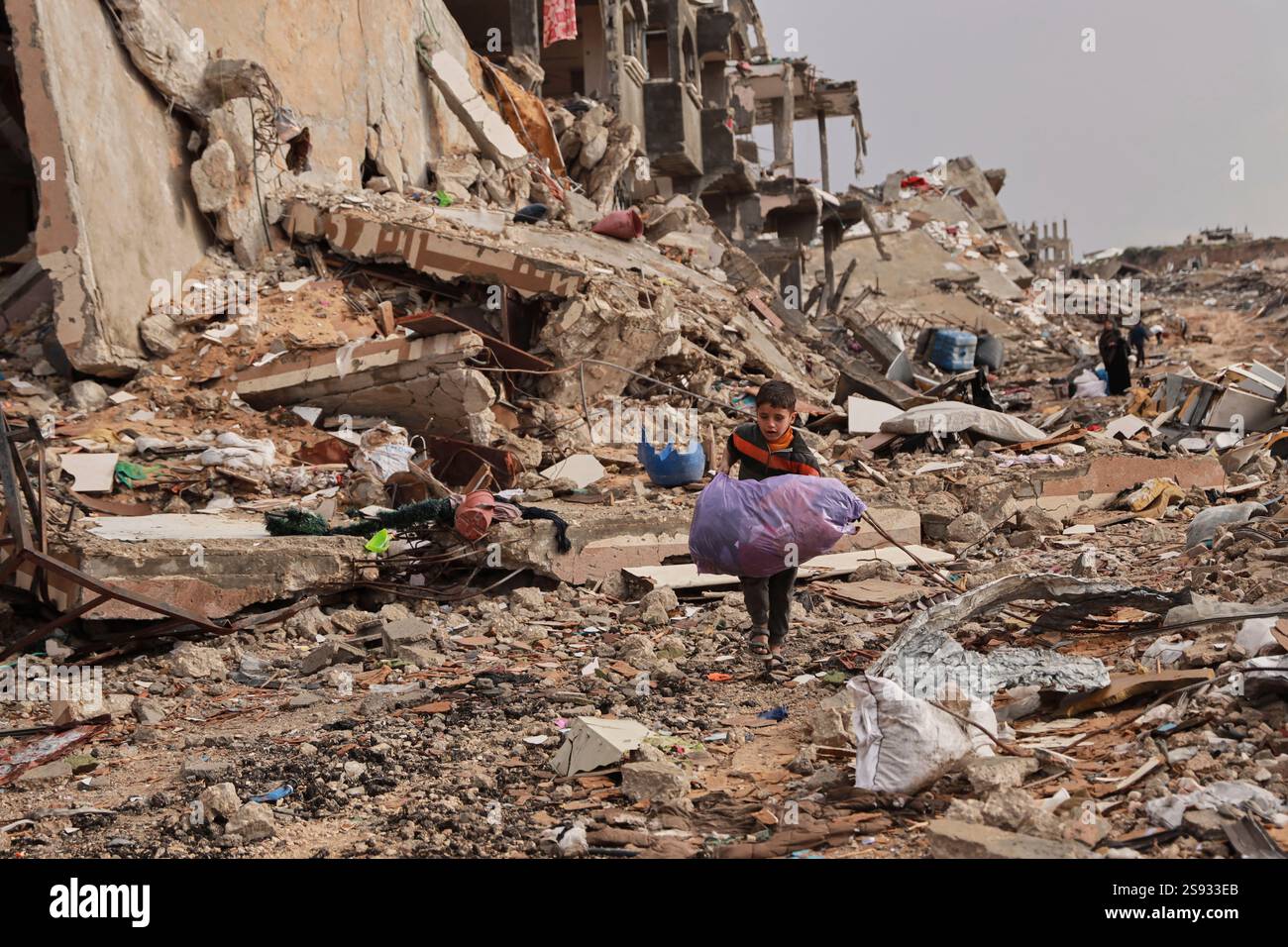 A Palestinian boy carries his belongings as he walks with his family ...