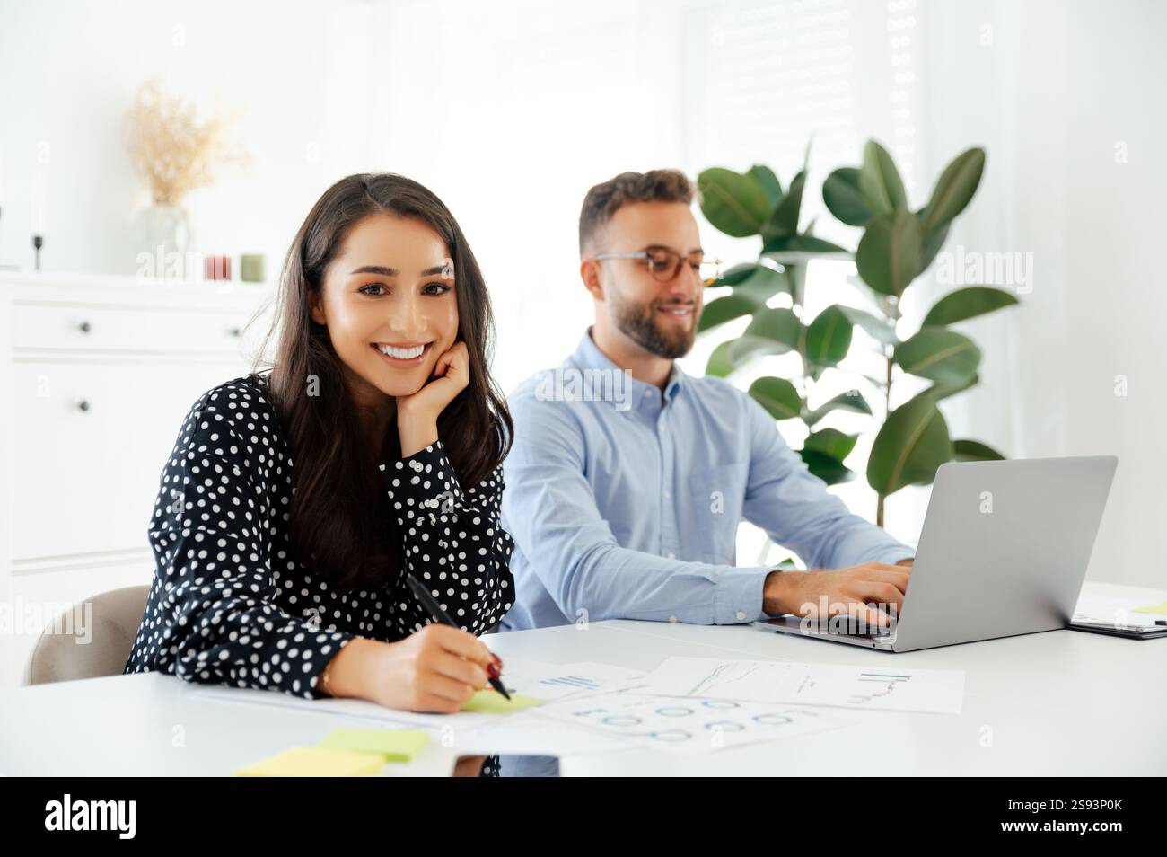 Cheerful young successful brunette businesswoman working at a desk in a ...