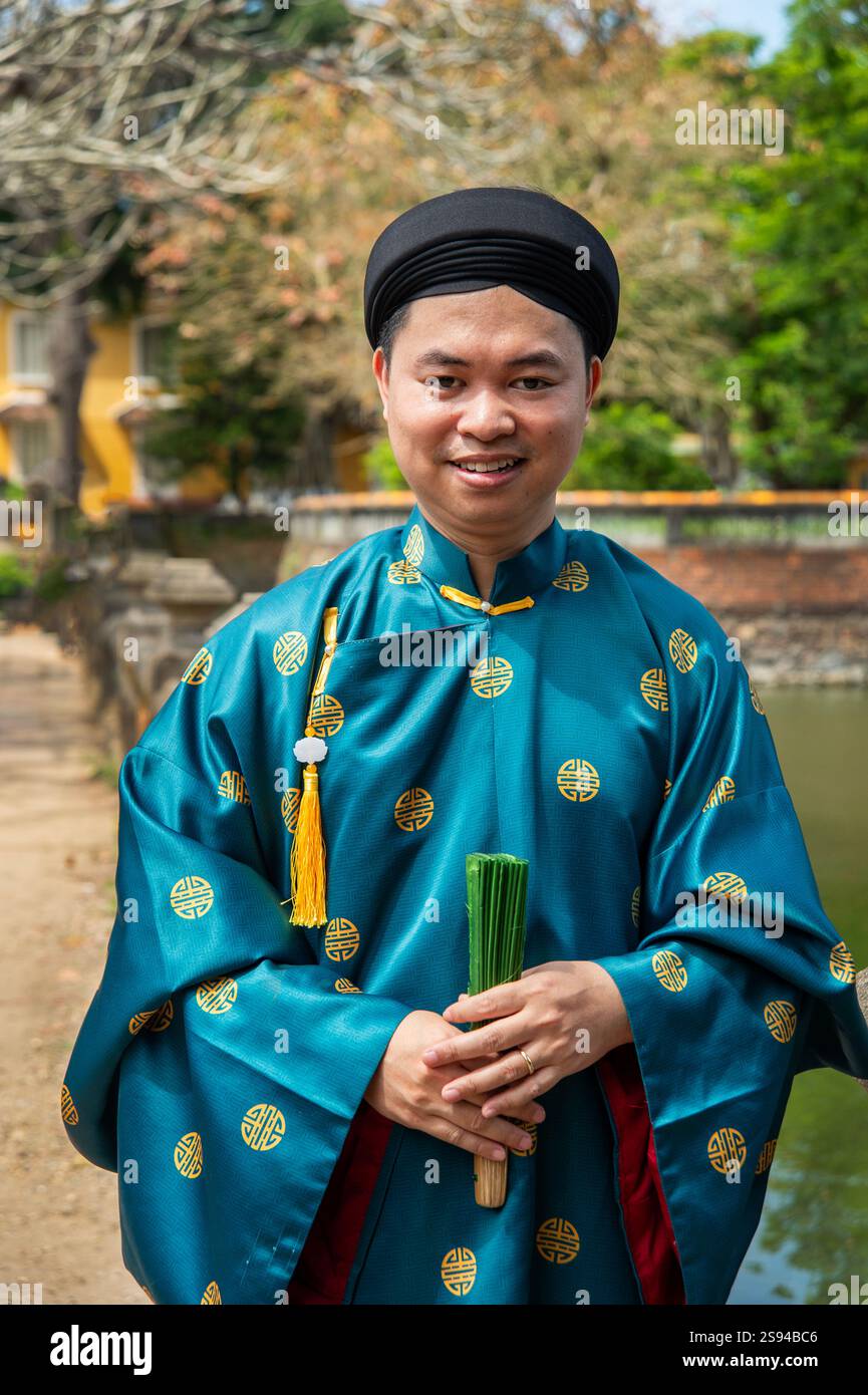 A smiling Vietnamese man dressed in traditional mandarin costume
