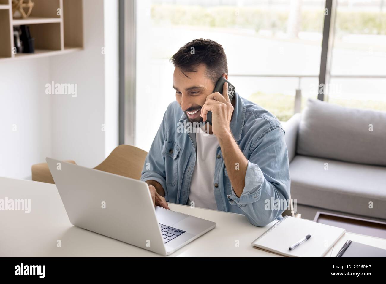 Smiling young 30s man talking on smartphone Stock Photo