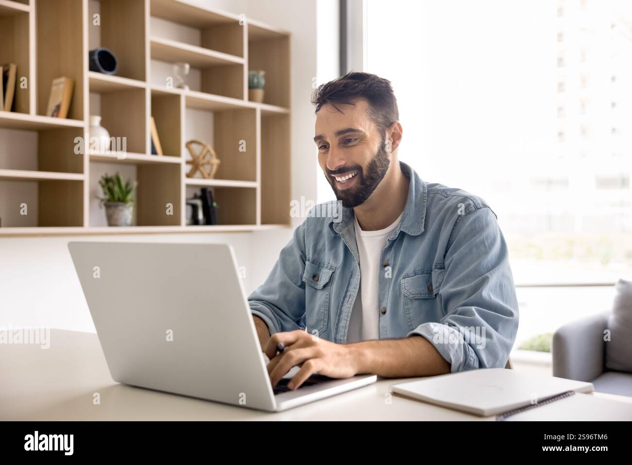 Young Hispanic man studying, e-learning, searching information using laptop Stock Photo