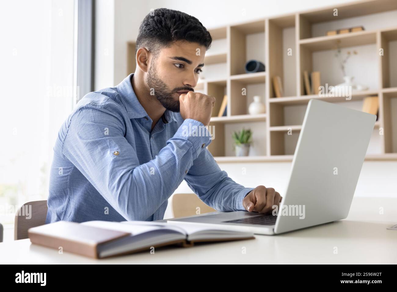 Focused reviewing data, analyzing reports using laptop Stock Photo