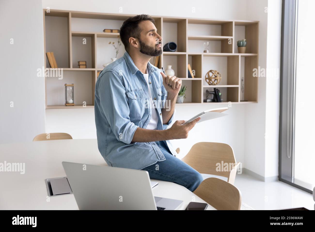 Pensive Hispanic employee working on creative ideas at modern workspace Stock Photo