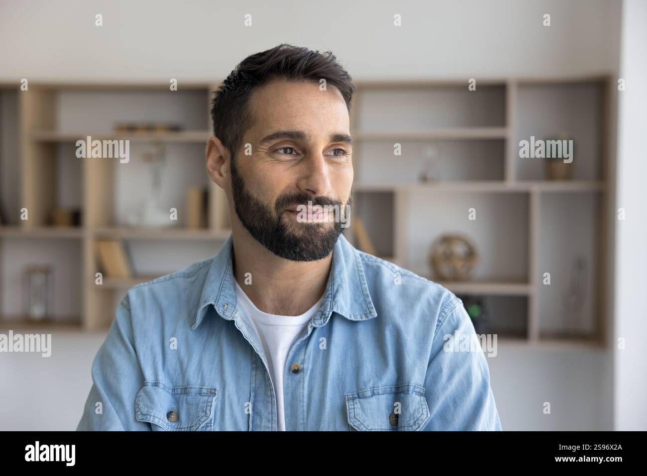 Thoughtful Hispanic man dressed in casual denim shirt posing indoors Stock Photo