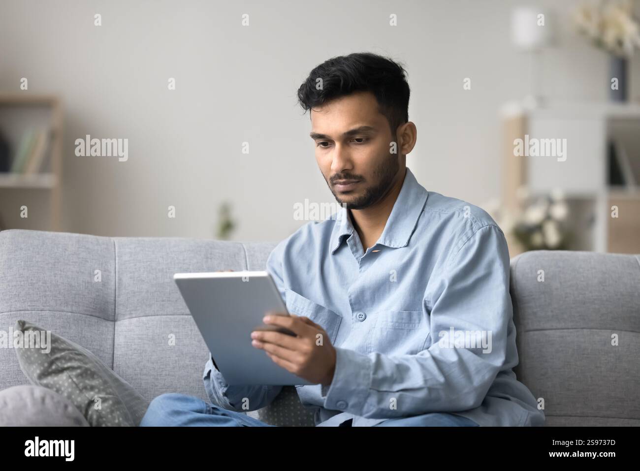 Focused young male freelancer working from home using digital tablet Stock Photo