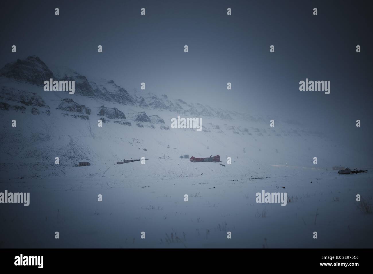 Buildings in the fog under snowy arctic mountain ridge in Longyearbyen ...