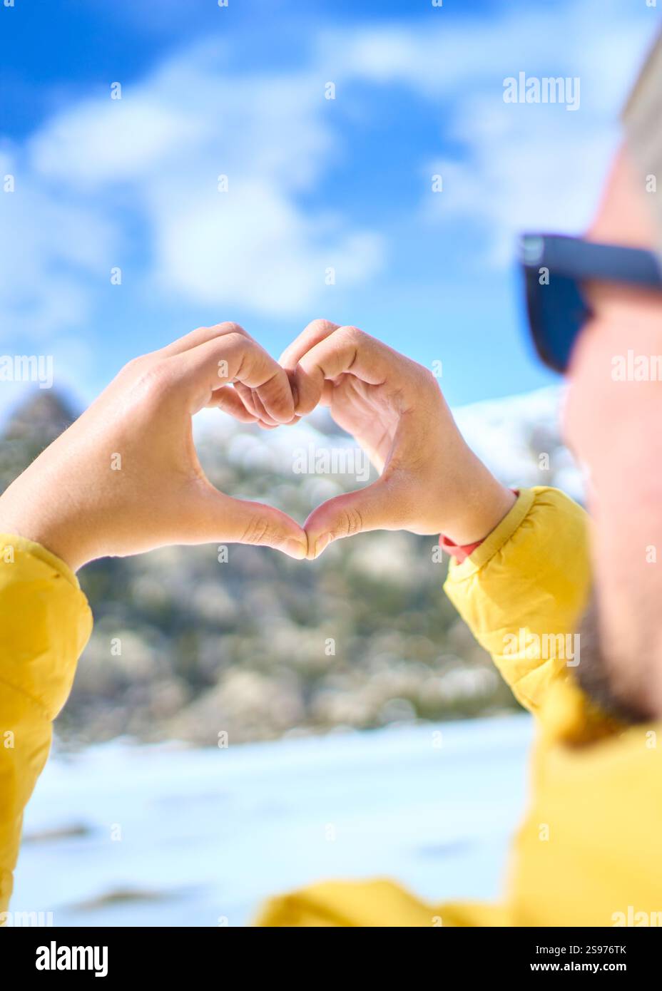 Man making heart shape with hands in winter landscape Stock Photo