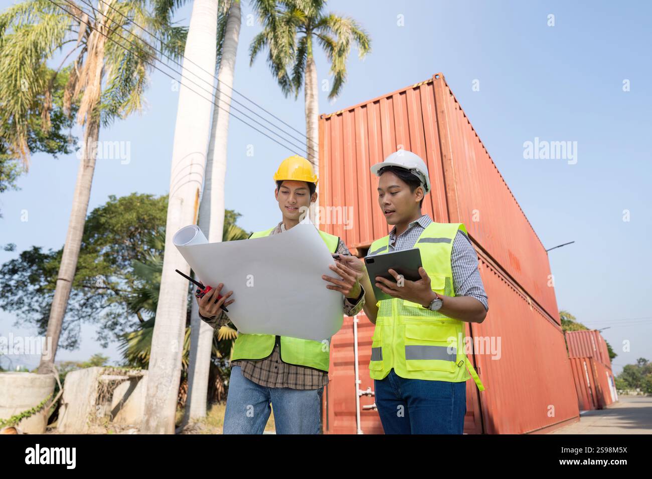 Engineers analyzing logistics plans and container management near shipping containers Stock Photo