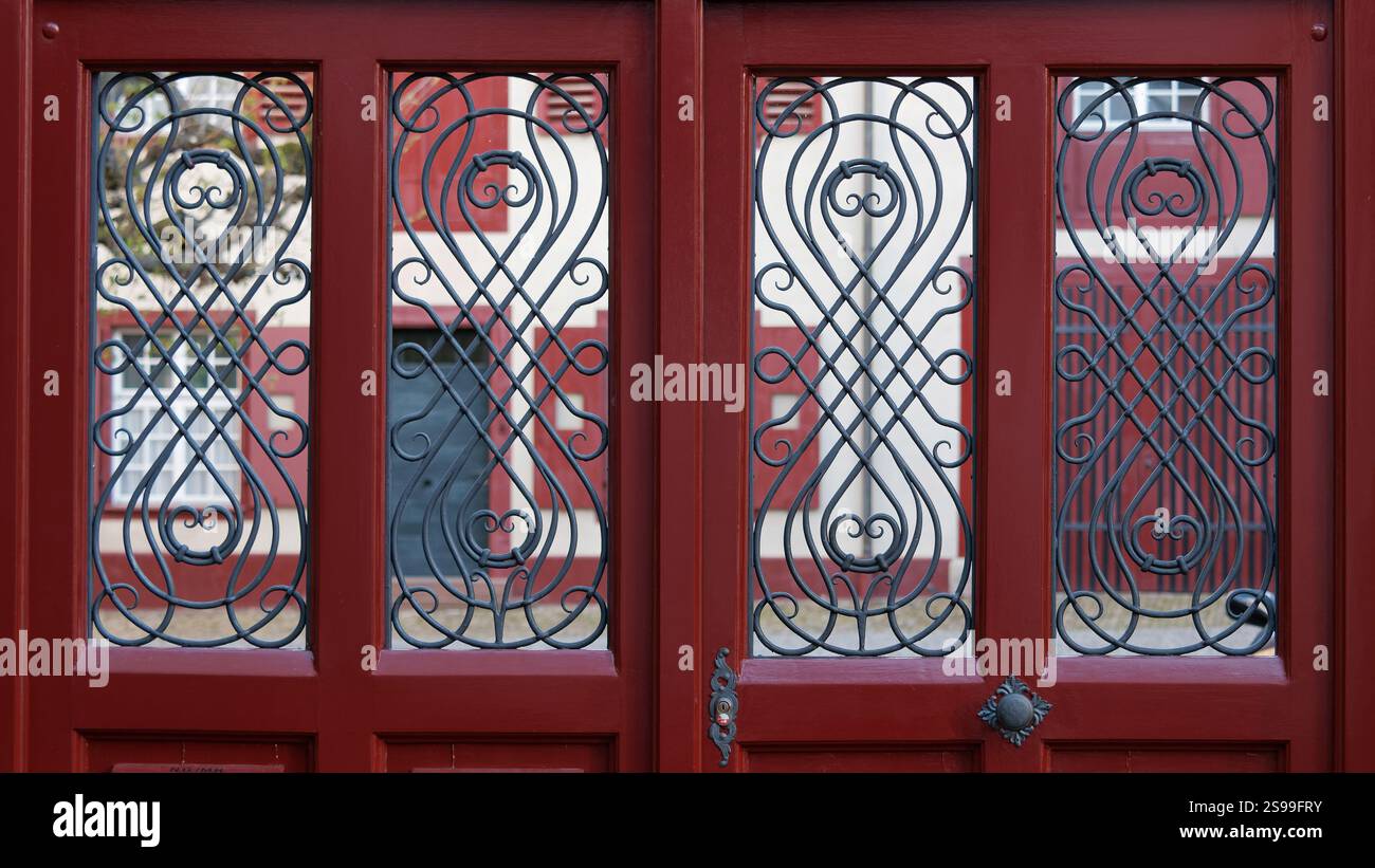 Red Door With Intricate Iron Latticework Featuring Symmetrical Decorative Patterns Stock Photo