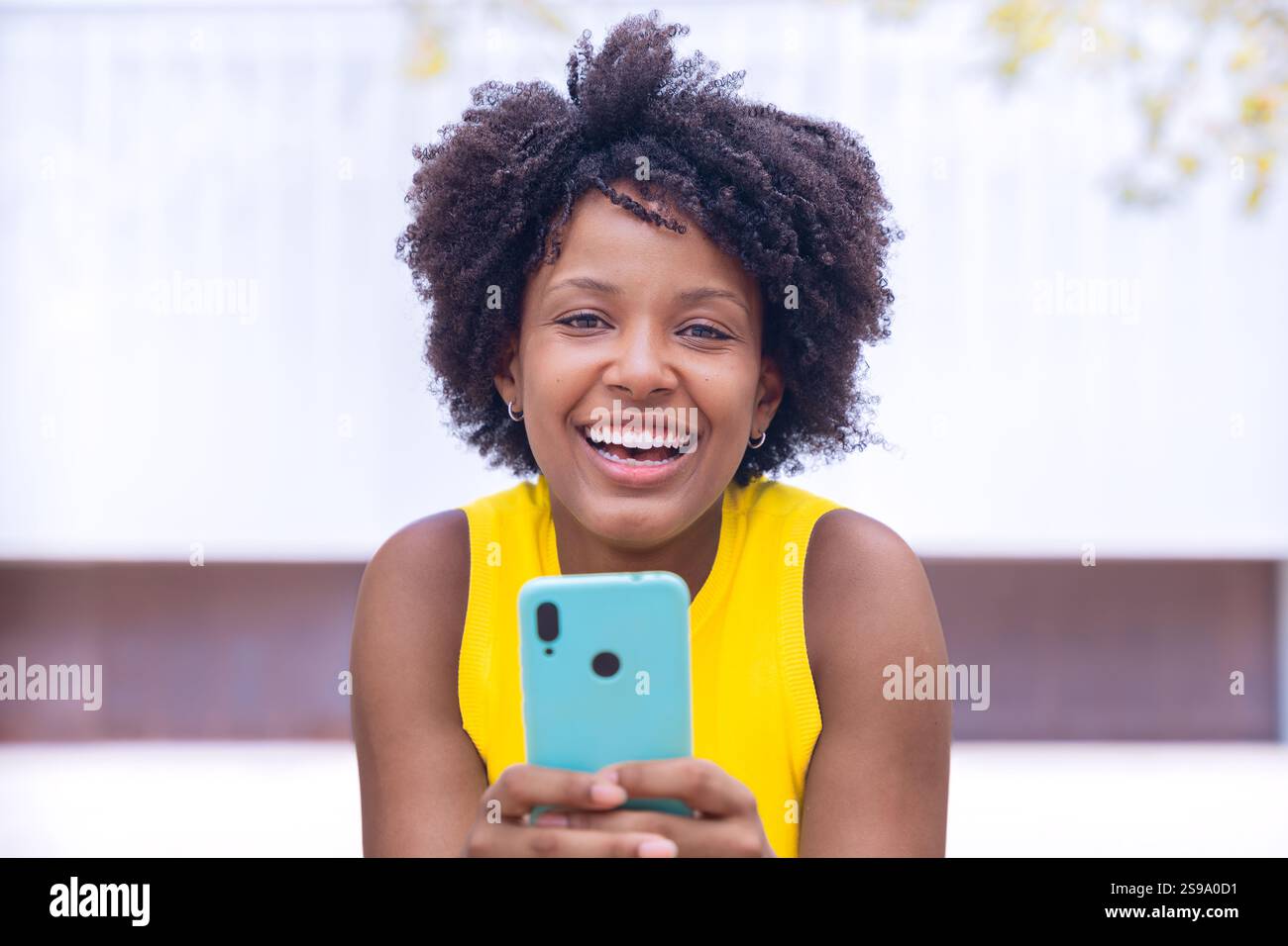 Smiling african american Young Woman Holding Smartphone Outdoors Stock Photo