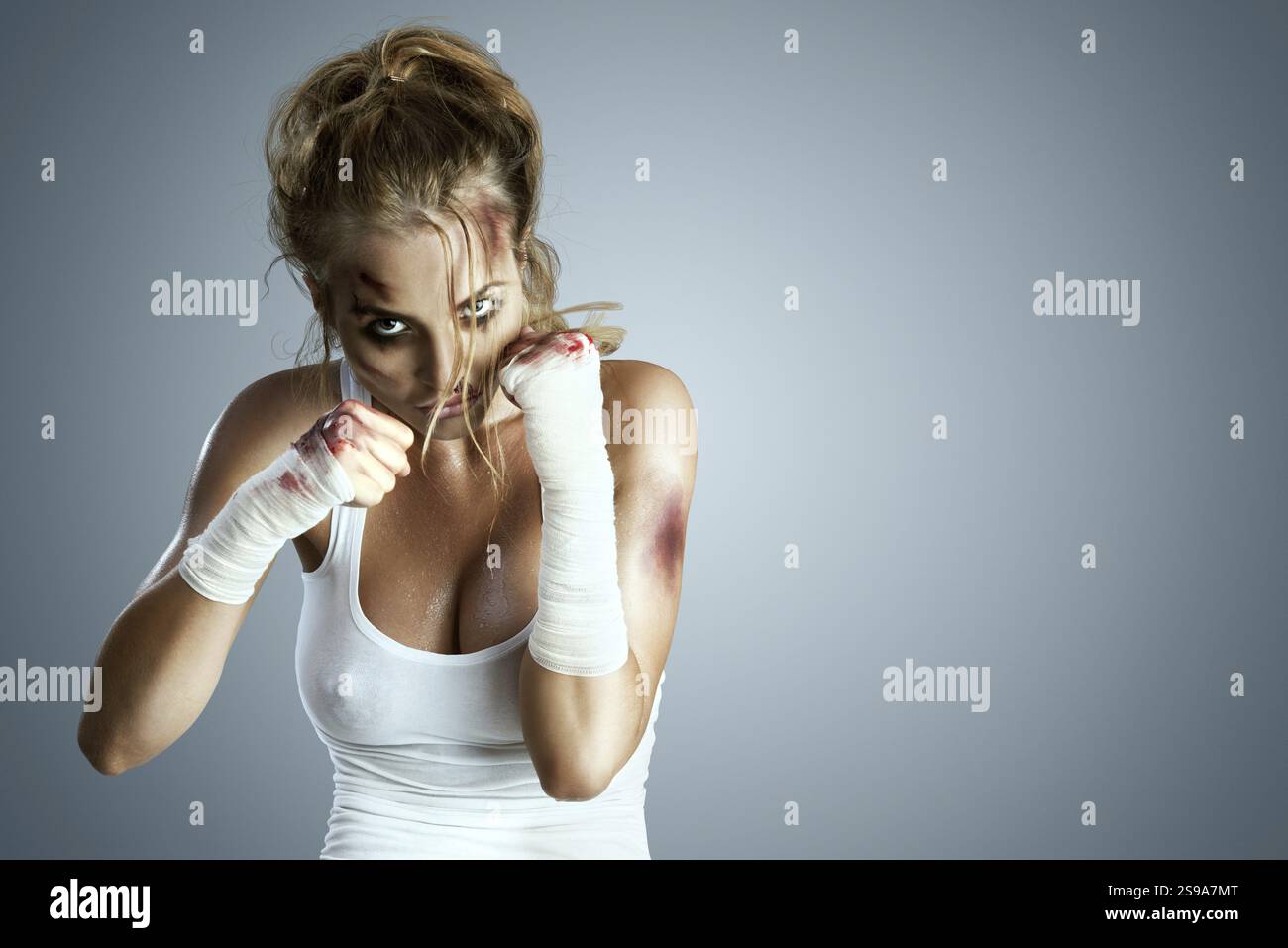 Aggressive female fighter with bruises, wearing a bloody bandage around ...