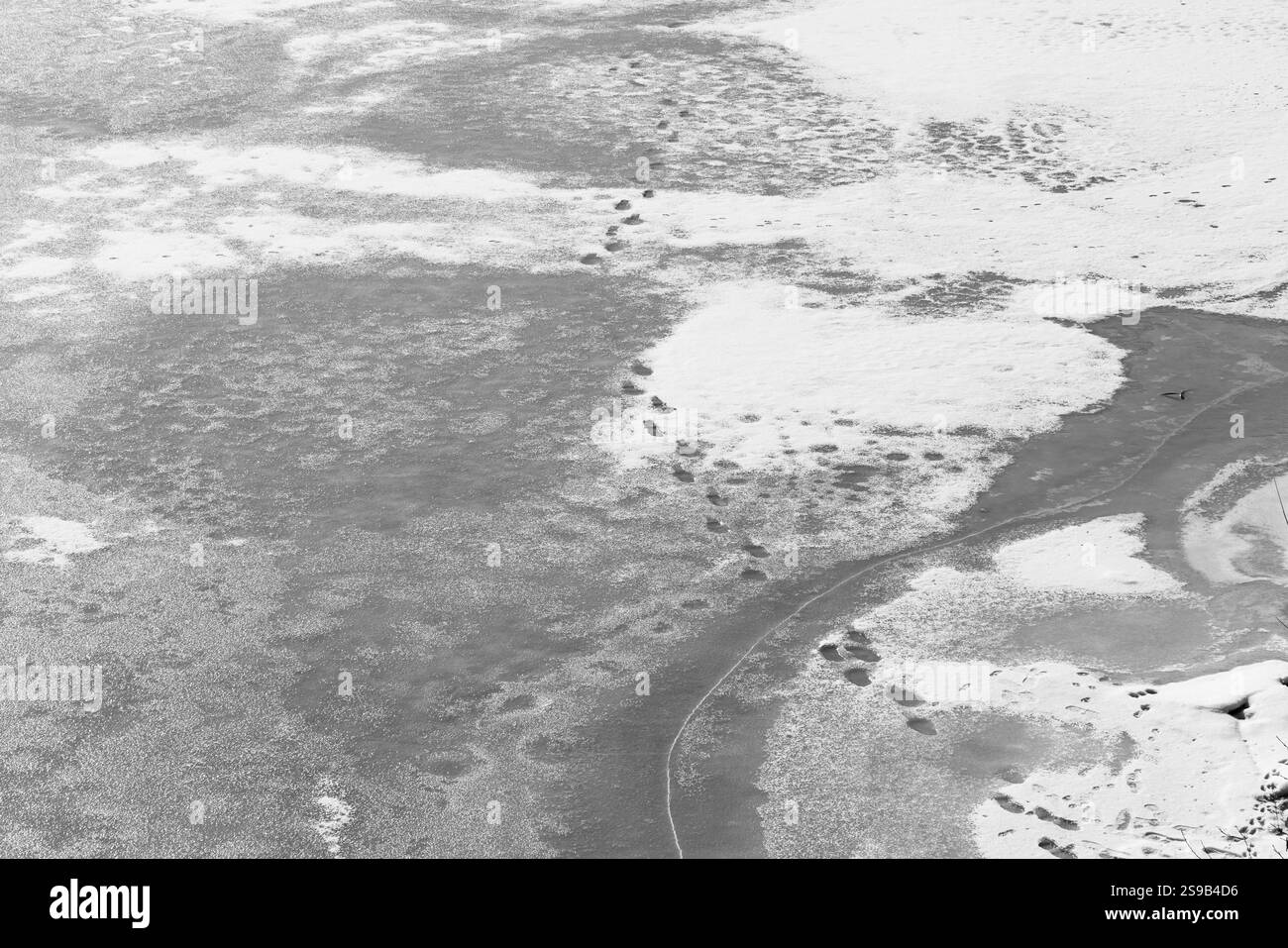 Footsteps in the Snow on a Frozen River Stock Photo