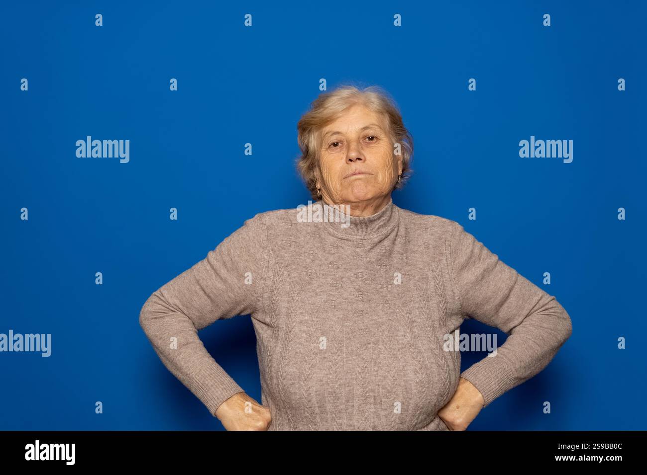 Caucasian woman in her 70s wearing a dark beige sweater with her arms ...