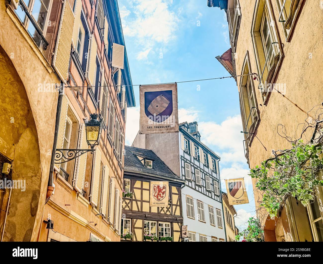 The ‘Les Tonneliers’ (The Coopers) hanging sign represents the historic trade of barrel-making, a nod to the Alsace region’s wine heritage. - Smartphone Captured Stock Image