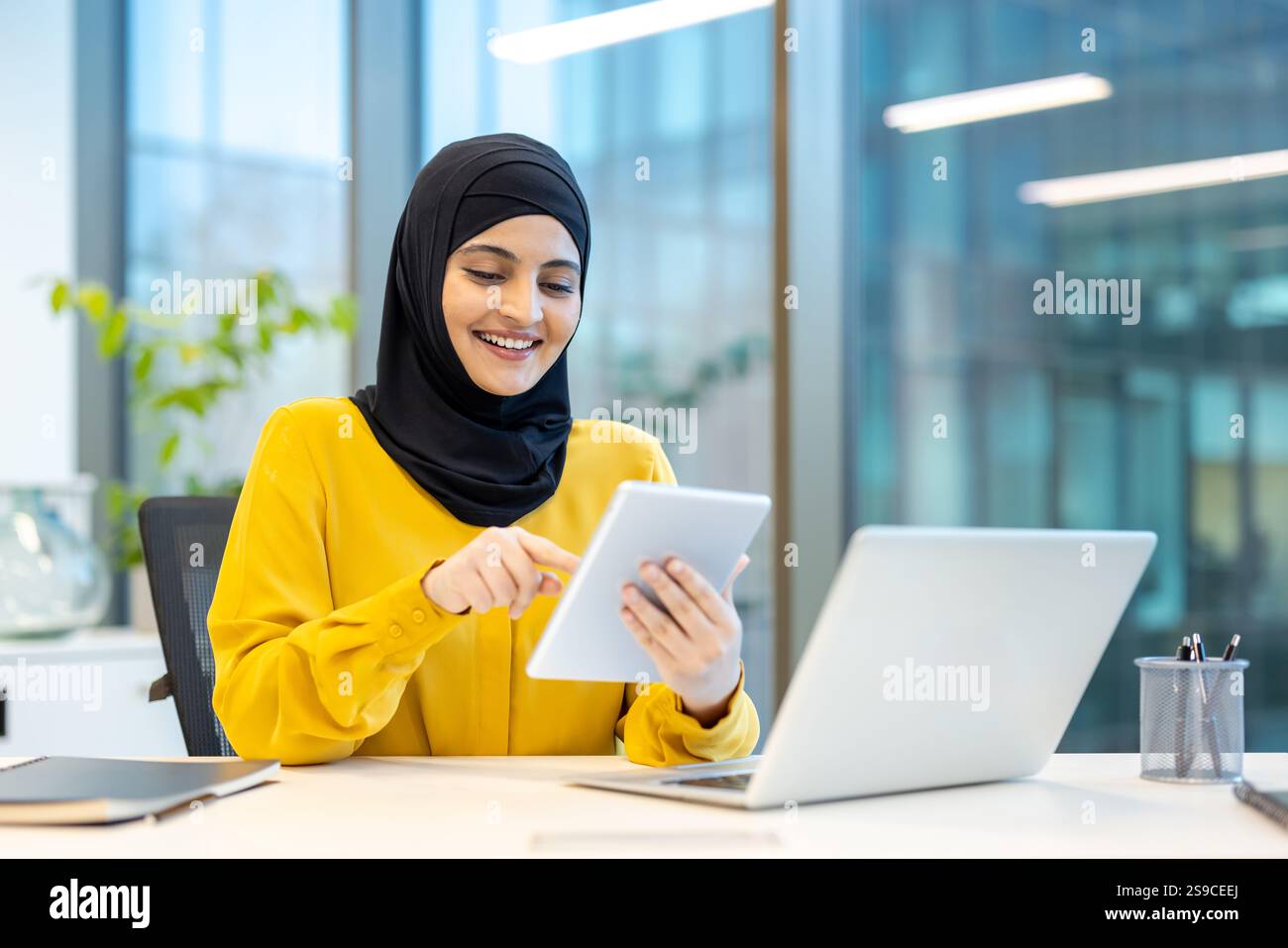 Successful woman in hijab using app on tablet computer. Arab office ...