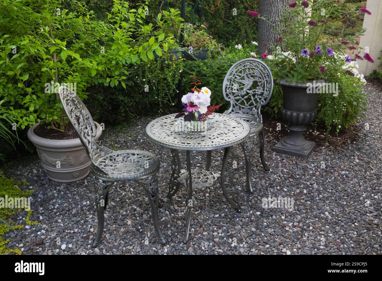 Victorian style table, chairs with cut flowers bouquet on gravel patio ...