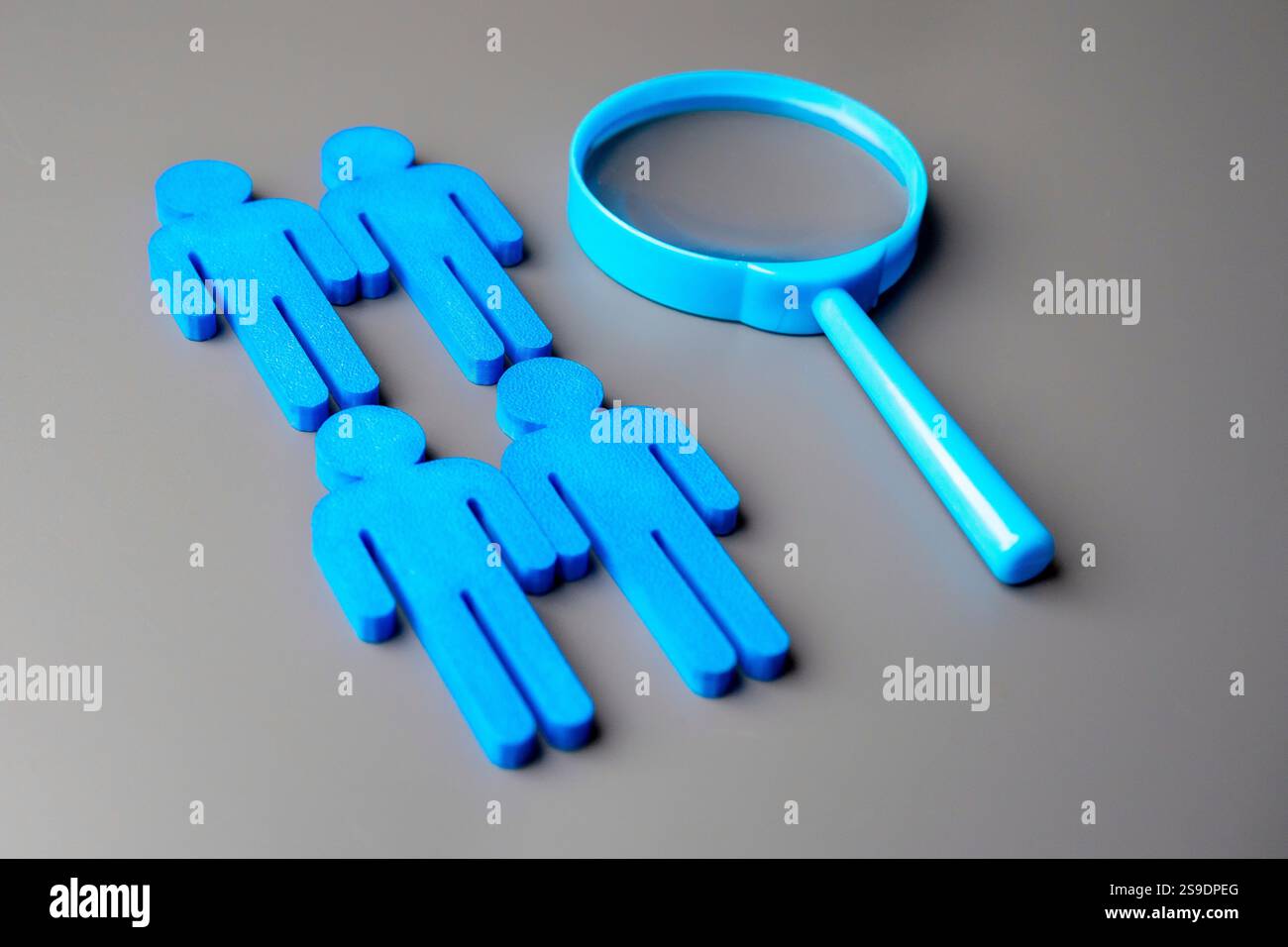 A magnifying glass and a group of blue figures. Recruitment and talent acquisition concept. Stock Photo