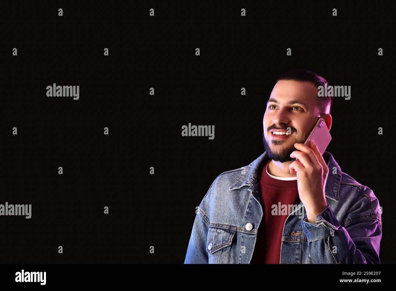 Young man talking by mobile phone on dark background Stock Photo