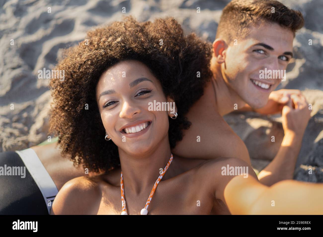 cheerful-multiracial-couple-taking-a-selfie-on-a-sandy-beach-during-a