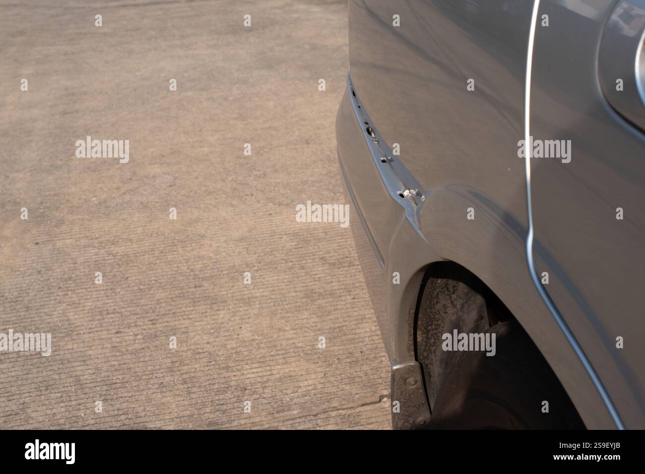 A close-up image of a damaged rear car bumper with visible cracks and misalignment. The photograph highlights the impact damage, exposing internal com Stock Photo