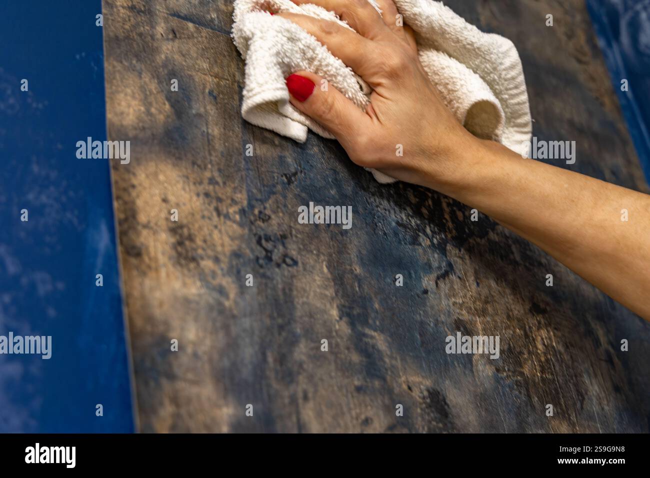 Woman in white T-shirt sticks wallpaper on the wall, wallpapering at home, bedroom renovation, woman wallpapers the wall herself Stock Photo