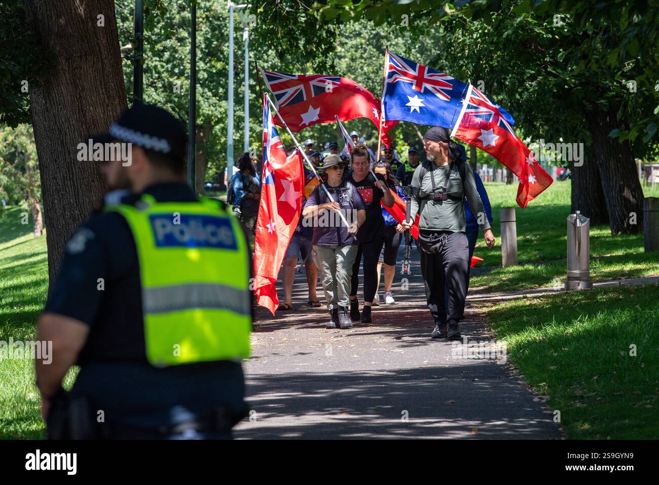 A small group of protesters carrying flags and watched by police walk ...