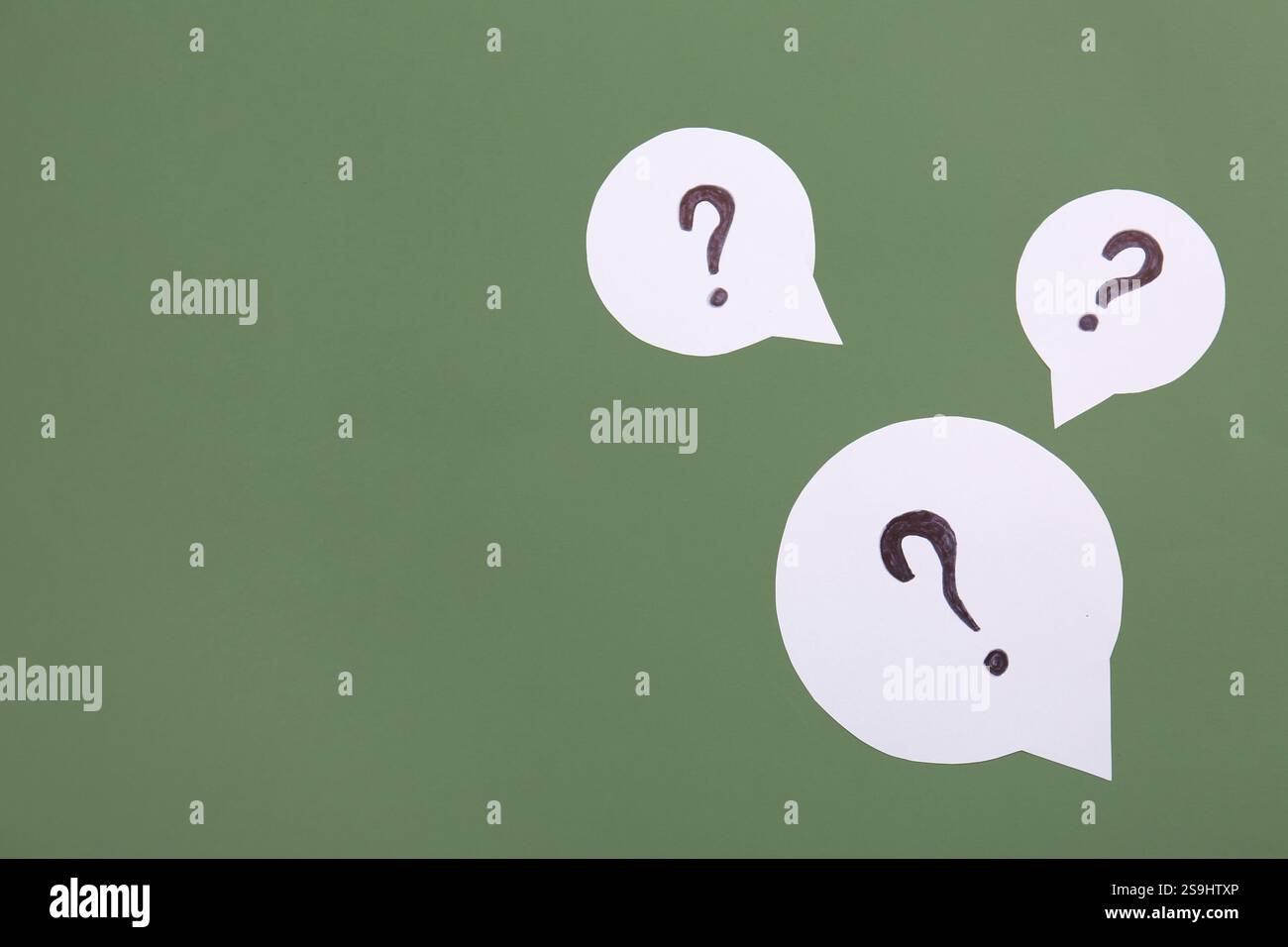 Speech bubbles with question marks on green background Stock Photo